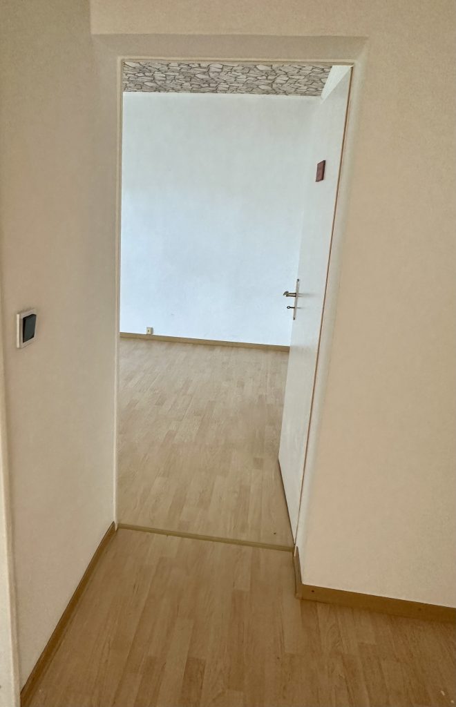 Blick durch eine Flurtür in einen hellen leeren Raum