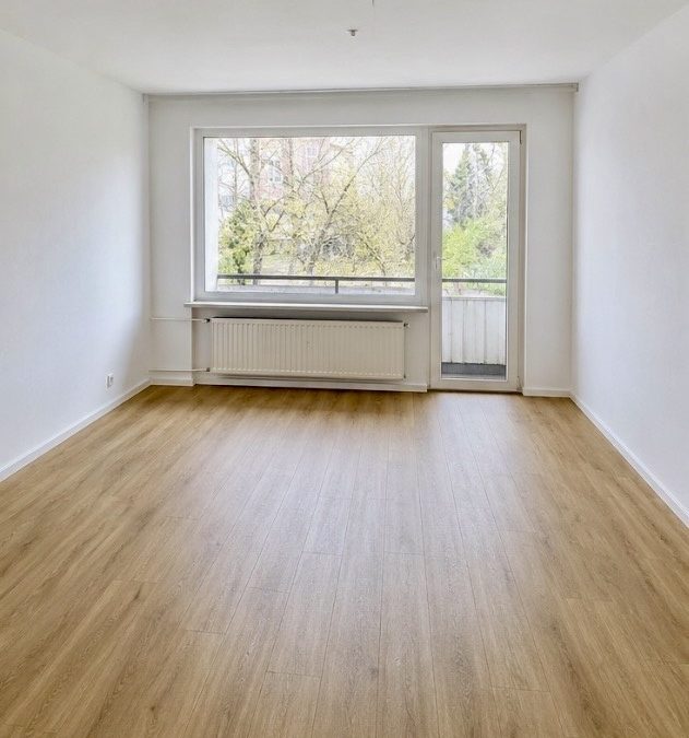 Hell saniertes Wohnzimmer mit hellem Eichenlaminat und Balkontür