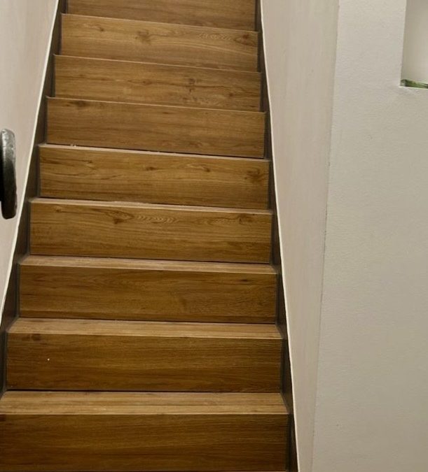Sanierte gerade Treppe mit Holzstufen und weißen Wänden