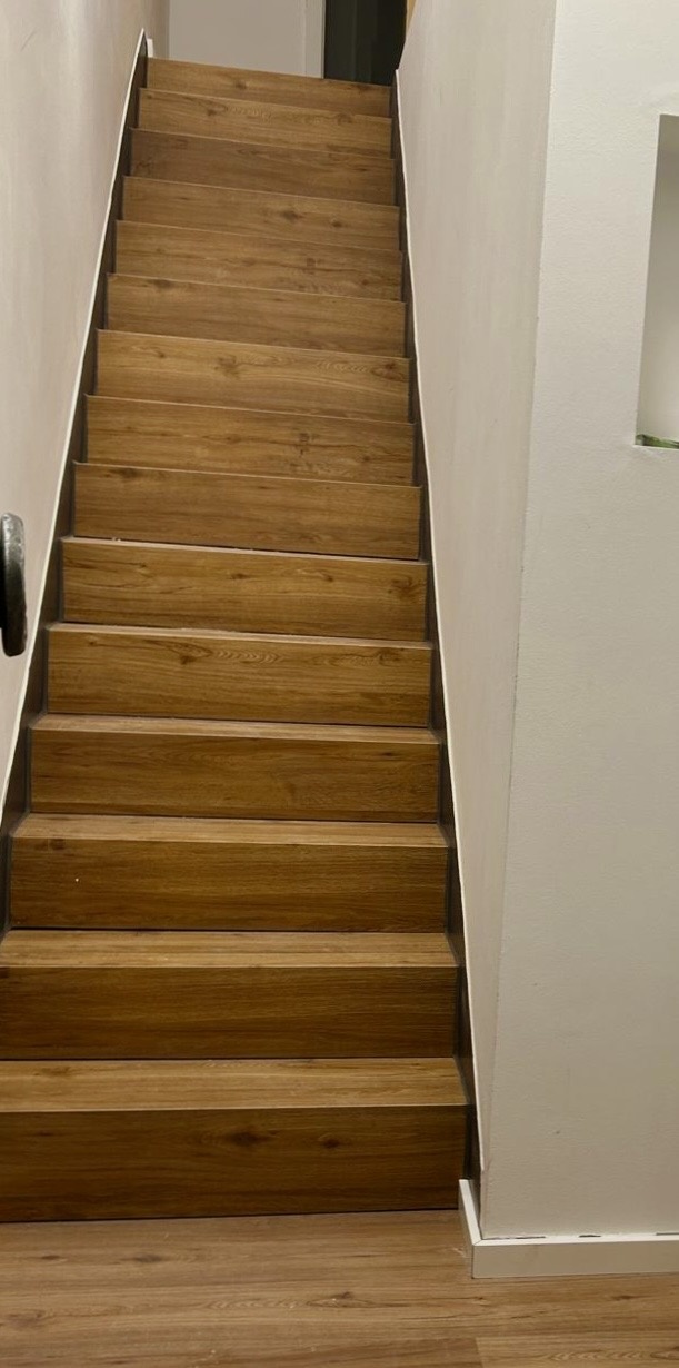 Sanierte gerade Treppe mit Holzstufen und weißen Wänden