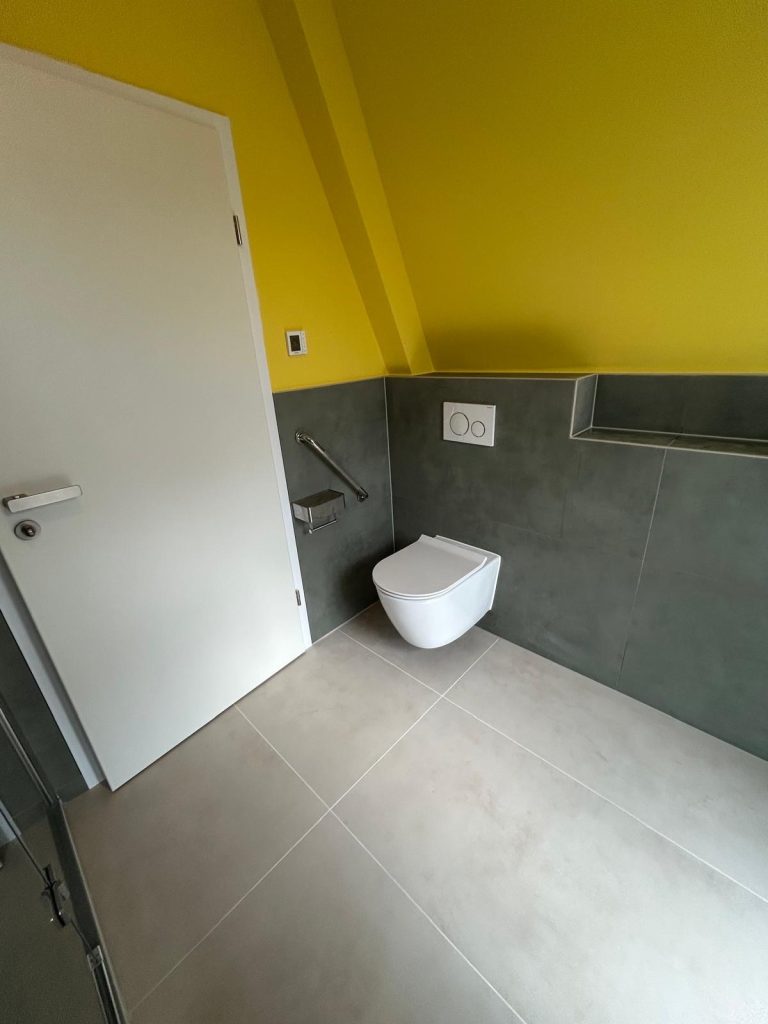 Gäste-WC mit Wand-WC, Betätigungsplatte und grauem Fliesensockel