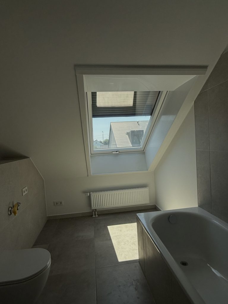 Dachbad mit Badewanne, Wand-WC, Heizkörper und Dachfenster