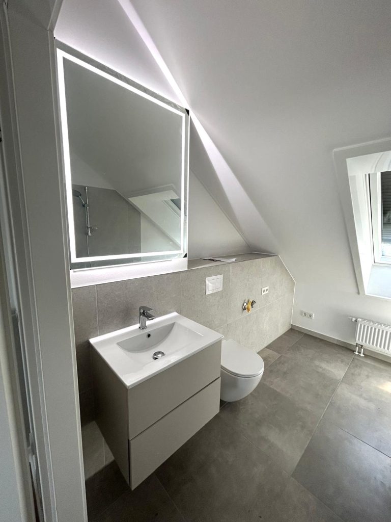 Dachbad mit beleuchtetem LED-Spiegel, weißem Waschtisch und Wand-WC