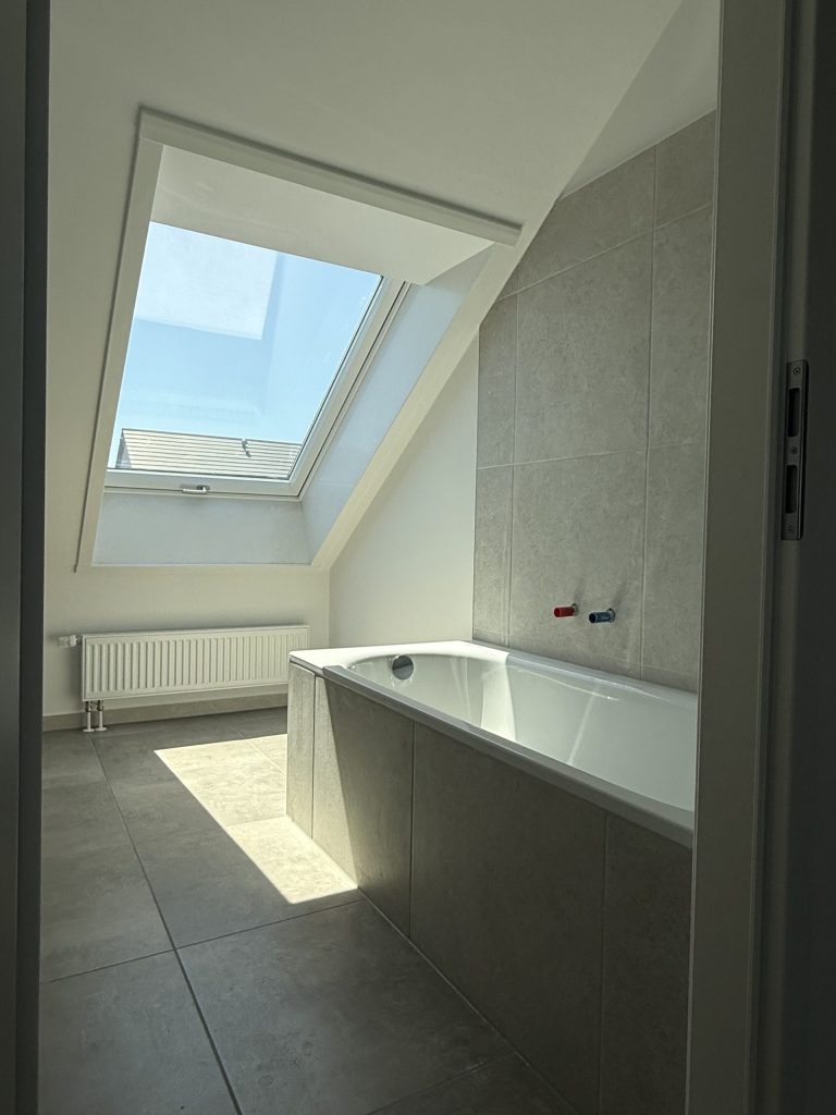 Helles Bad mit großem Dachfenster, Heizkörper und eingebauter Badewanne