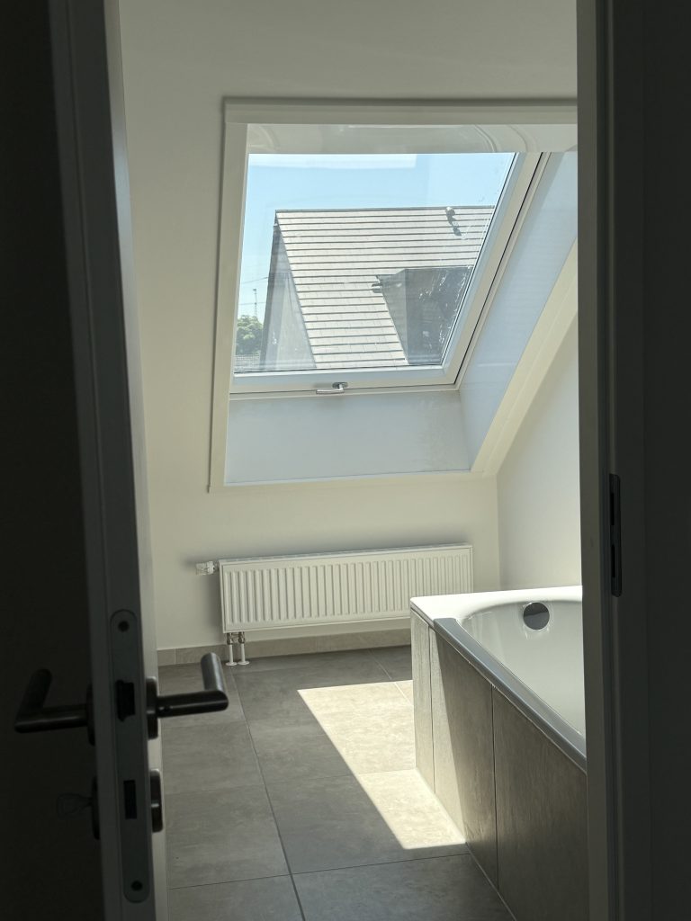Bad mit Dachfenster, Heizkörper und Badewanne im Sonnenlicht