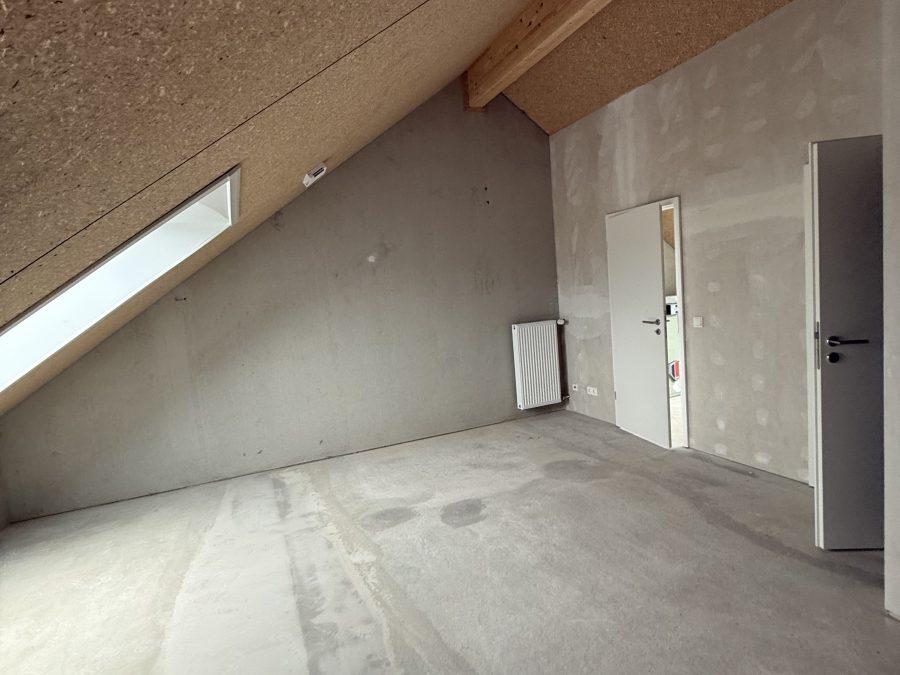 Großer Dachraum im Rohbau mit OSB-Decke, Holzsparren und zwei Türen
