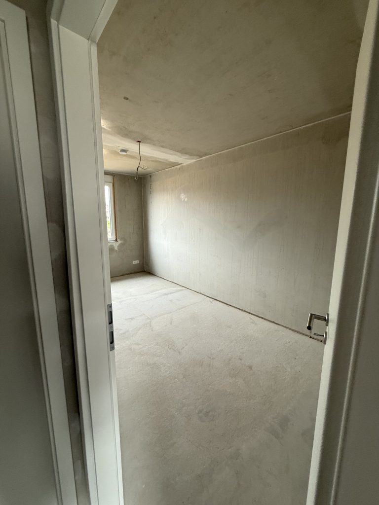 Blick durch eine Tür in ein leeres Zimmer im Rohbau