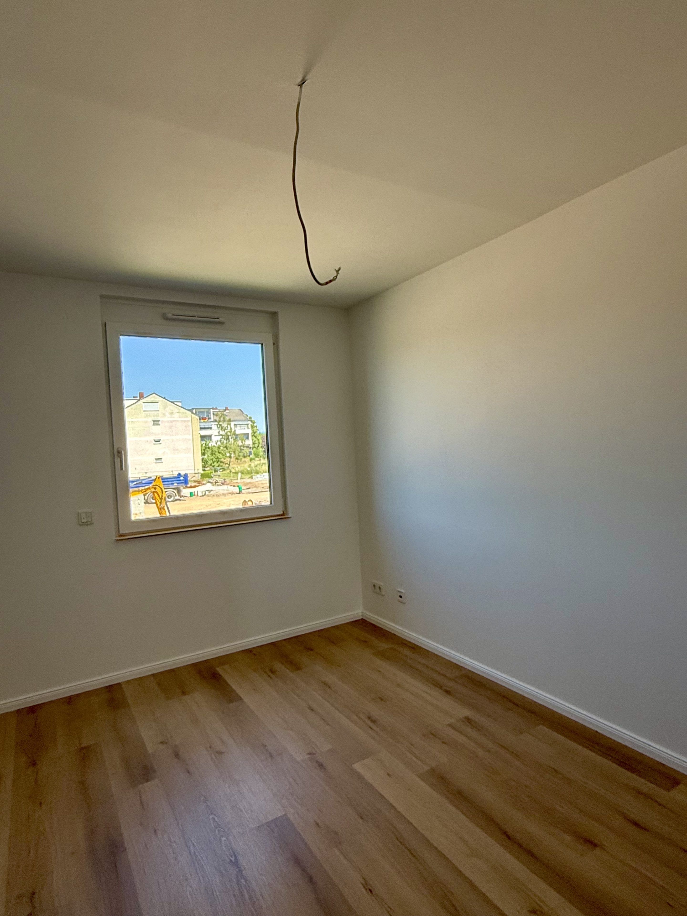 Leerer weißer Raum mit Fenster und Vinylboden in Eichenoptik